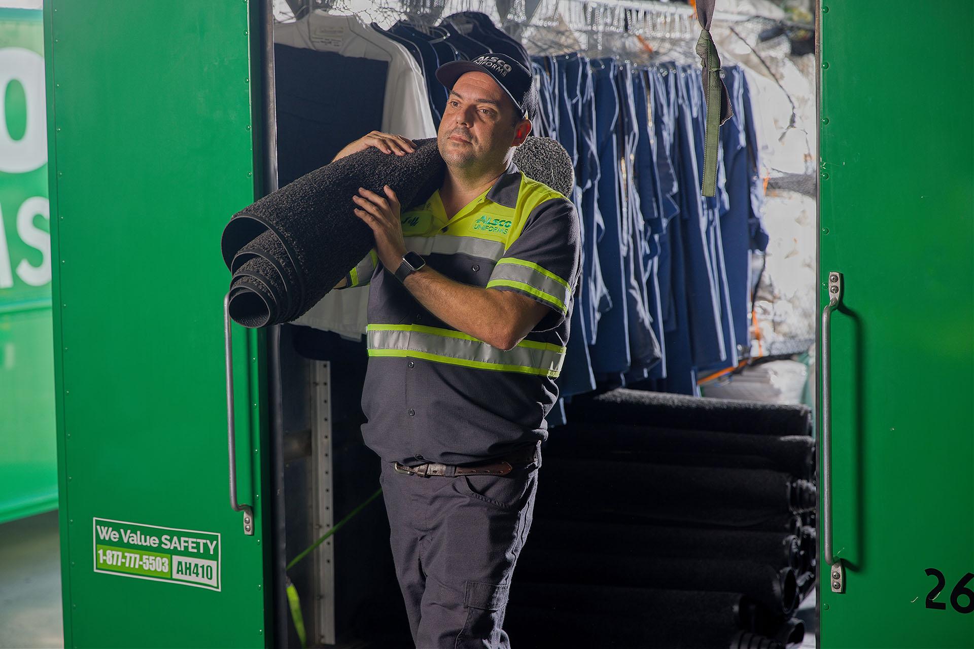 Alsco worker carrying a floor mat