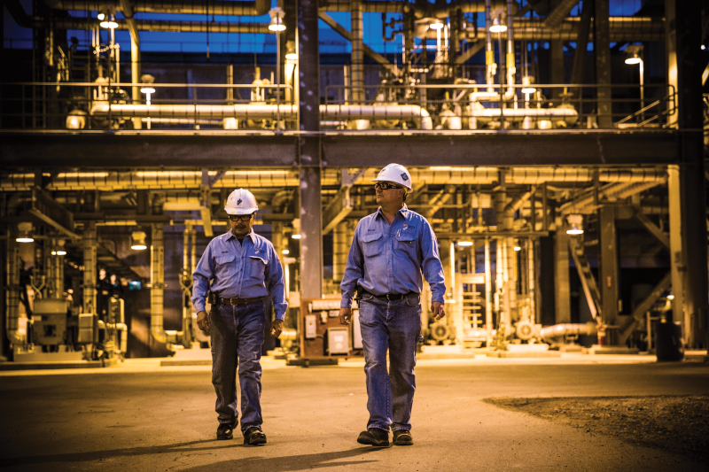 Two uniformed men working in a refinery.