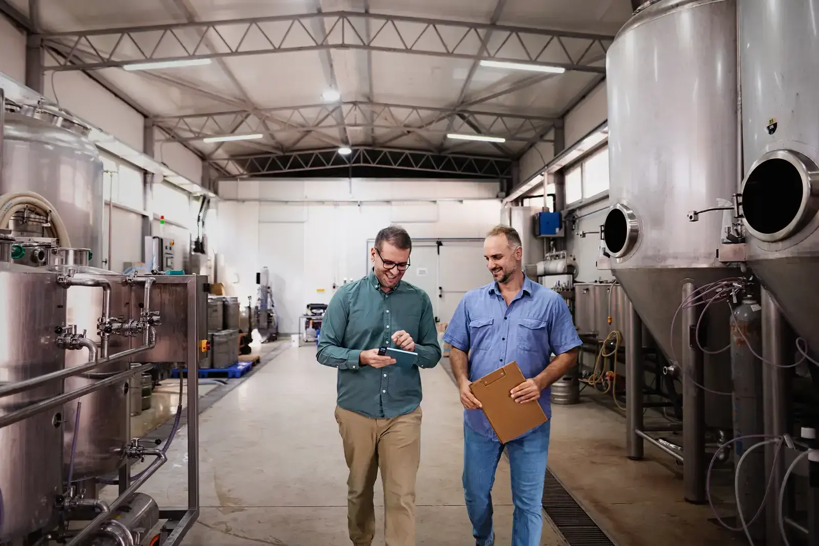 Two men running a checklist of facility service option in a brewery