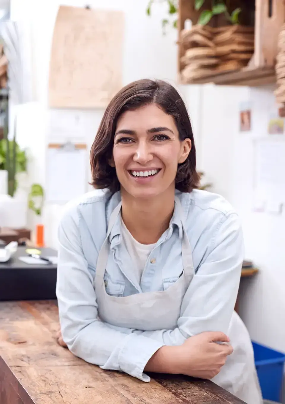 Female business owner leaning on counter in apron