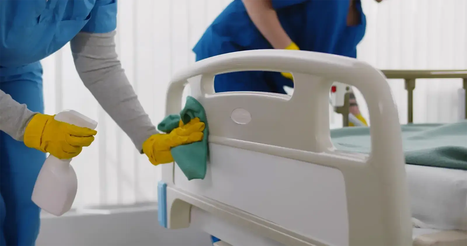 A hospital bed being disinfected with a cleaning cloth