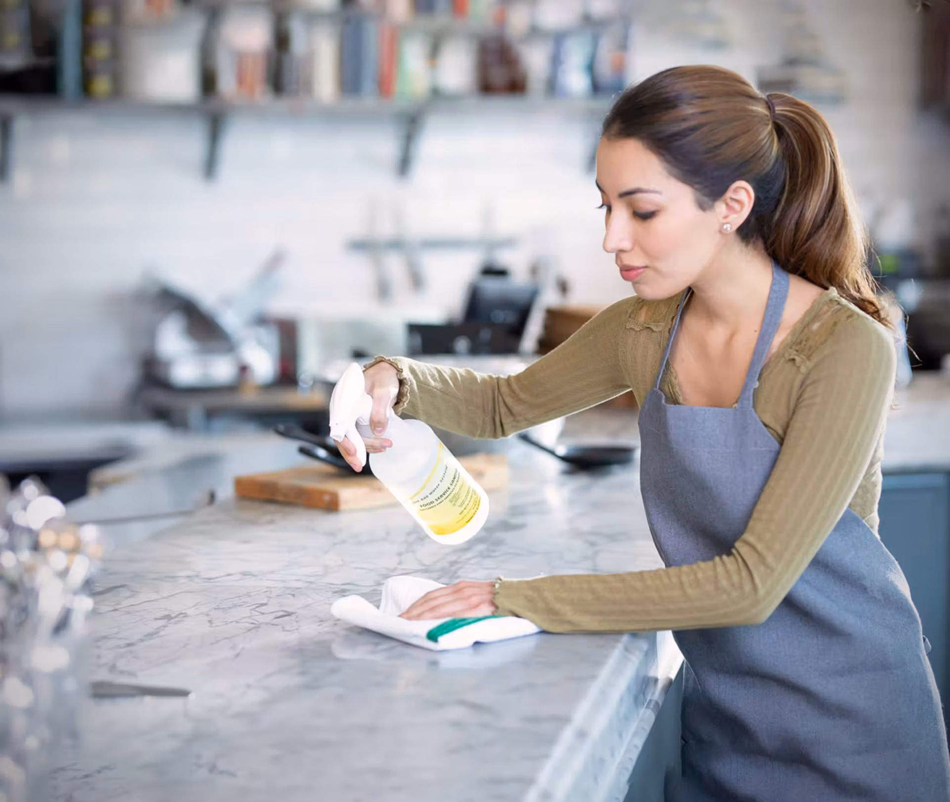 Worker using cleaning supplies on a marble countertop