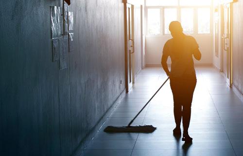 Worker mops a floor in a hallway