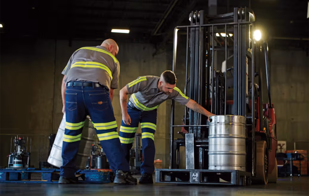 Hi-vis industrial workers moving a barrel