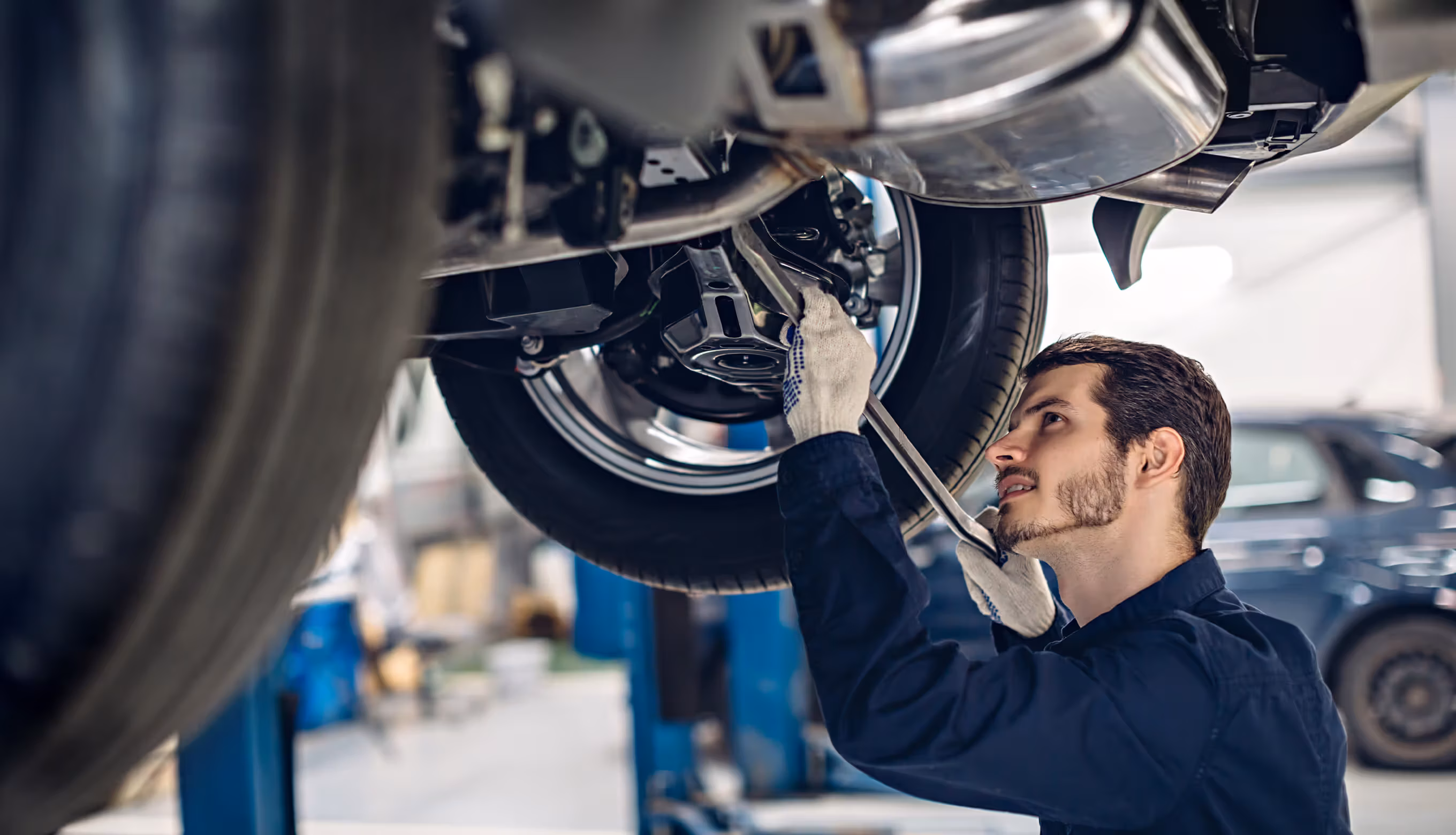 Auto mechanic working on raised car engine