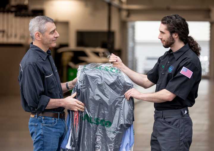 Alsco employee handing off cleaned uniform to customer